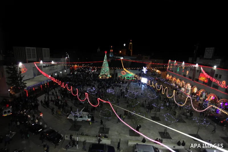 Palestinians celebrate the lighting of the Christmas tree in Manger Square, outside the Church of the Nativity, in the West Bank biblical town of Bethlehem, the traditional birthplace of Jesus as preparations for Christm...
