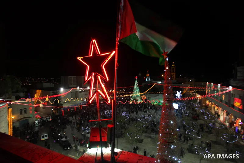 Palestinians celebrate the lighting of the Christmas tree in Manger Square, outside the Church of the Nativity, in the West Bank biblical town of Bethlehem, the traditional birthplace of Jesus as preparations for Christm...