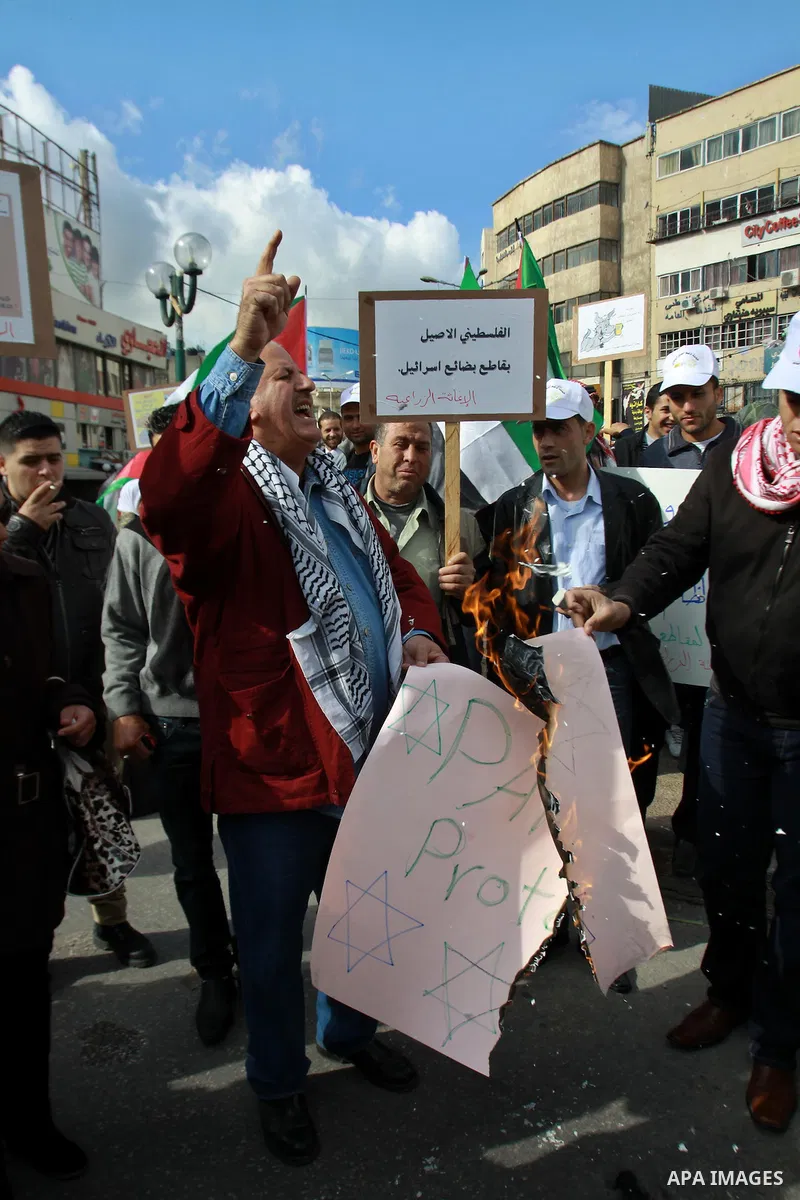 Palestinians burn a placard reading "Paris Protocol" and bearing the Star of David during a protest against the Paris Protocol and the Oslo Agreement, both key accords which govern economic ties between Palestinians and...