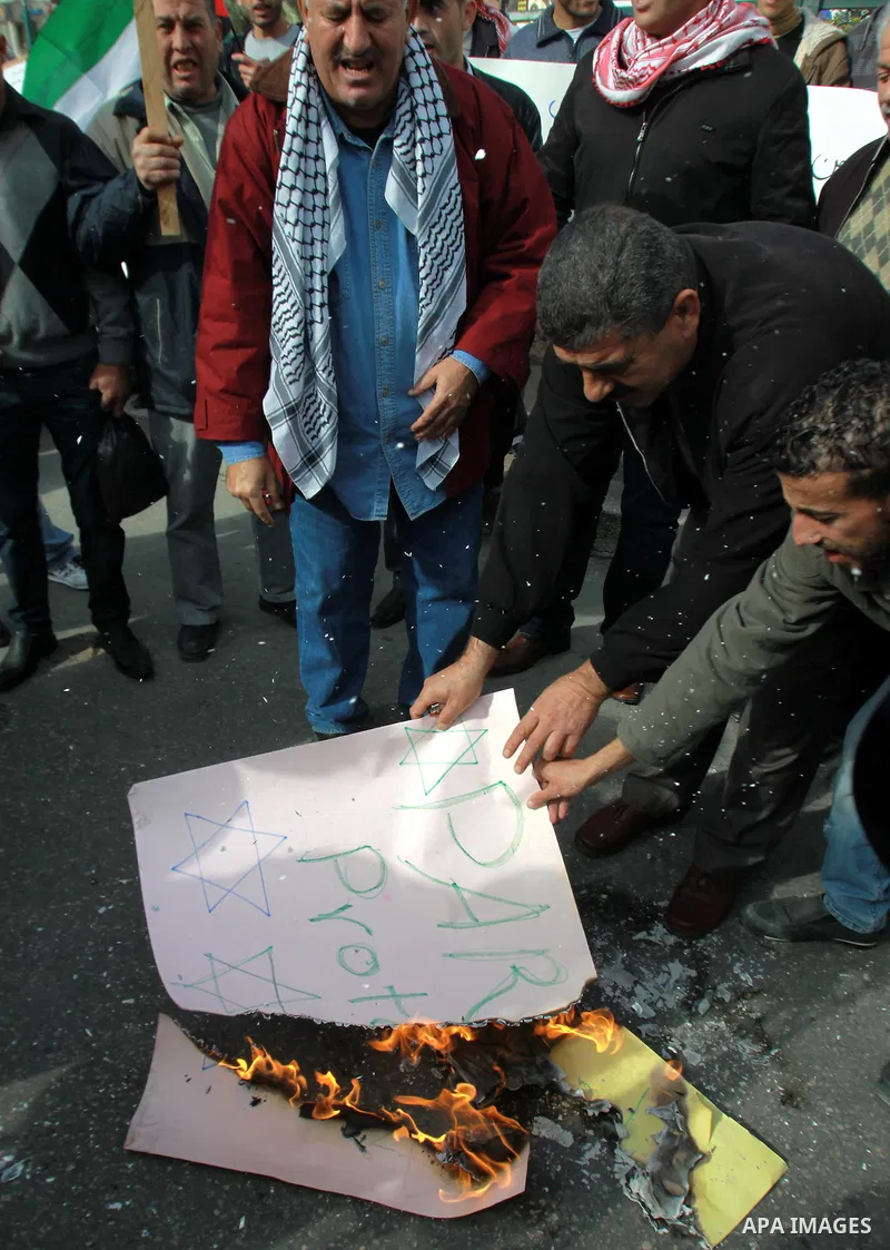 Palestinians burn a placard reading "Paris Protocol" and bearing the Star of David during a protest against the Paris Protocol and the Oslo Agreement, both key accords which govern economic ties between Palestinians and...