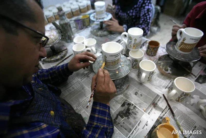 Palestinian workesr paint on a ceramic cup by using traditional skills in the West Bank city of Hebron on 16 December, 2012. Palestinian ceramics are produced at traditional family-owned factories in Hebron and other cit...