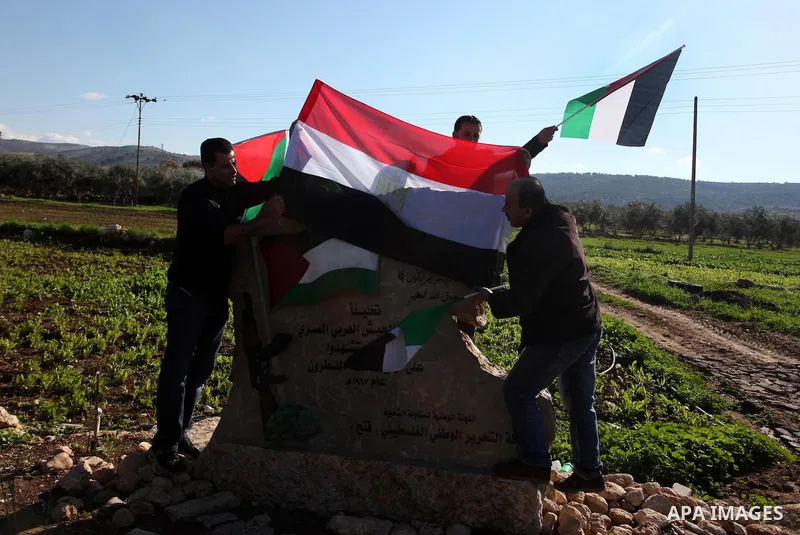 Palestinian and foreign activists hold Palestinian and Egyptian national flags as they demonstrate next to a monument commemorating the death of Egyptian soldiers killed during the 1967 Six-Day war in the West Bank villa...