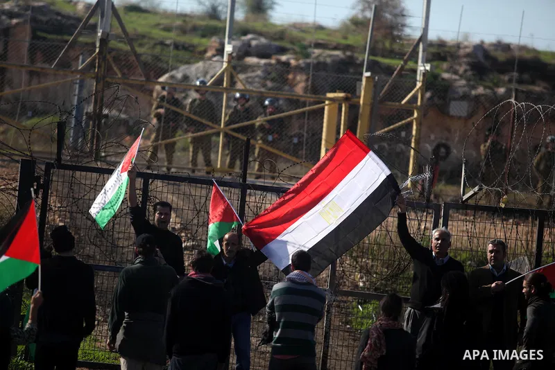 Palestinian and foreign activists hold Palestinian and Egyptian national flags as they demonstrate in front of Israeli soldiers against the destruction of a monument commemorating the death of Egyptian soldiers killed du...