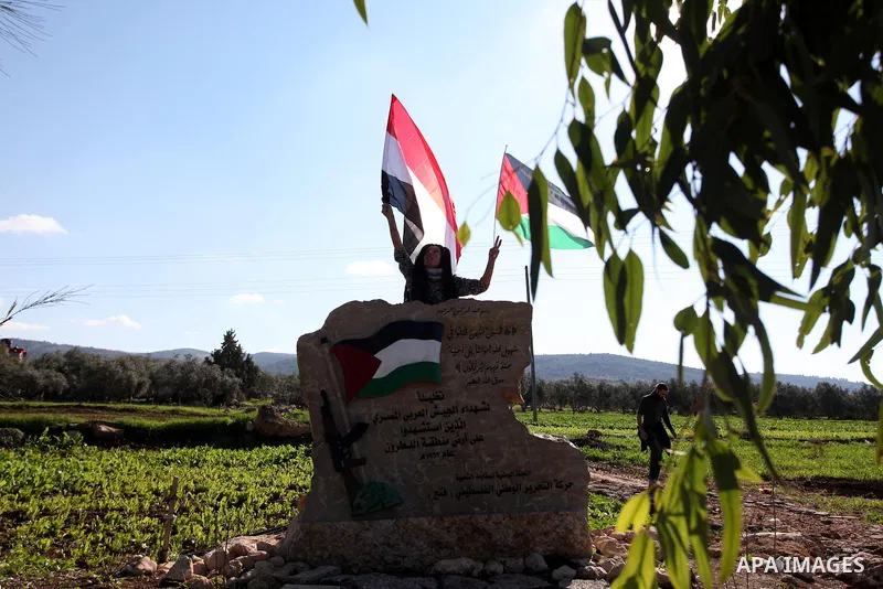 A Palestinian activist holds Palestinian and Egyptian national flag as she demonstrate next to a monument commemorating the death of Egyptian soldiers killed during the 1967 Six-Day war in the West Bank village of Beit N...