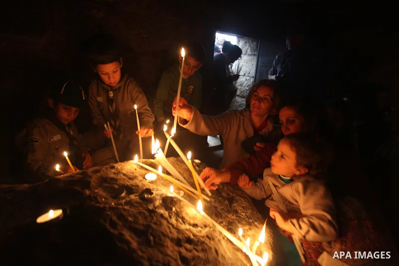 Palestinian Orthodox Christians light candles in a cave at the ancient monastery of St. Barbara, in the nearby hills close to the village of Abud, in the Israeli occupied West Bank, on December 16, 2012, as they celebrat...