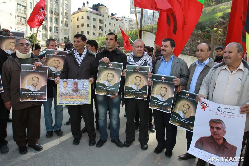 Palestinians hold pictures of their prisoner relatives in Israeli jails as they gather in a weekly activity calling for their liberty at the Red Cross headquarters in the West Bank city of Nablus on December 17, 2012. Ph...