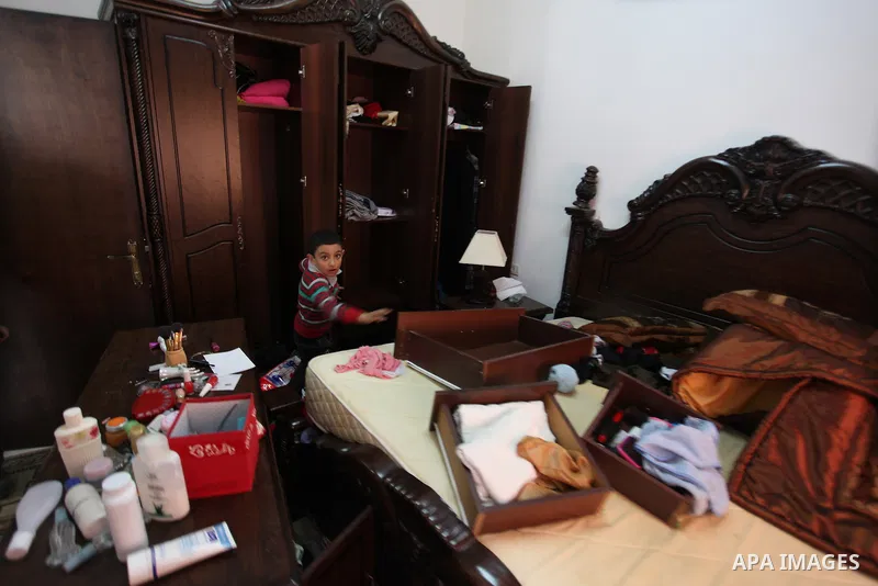 Palestinians look at ransacked belongings after Israeli soldiers entered the house and arrested three brothers and another Palestinian, who was wounded, in the northern West Bank village of Beit Rima, near Ramallah on De...
