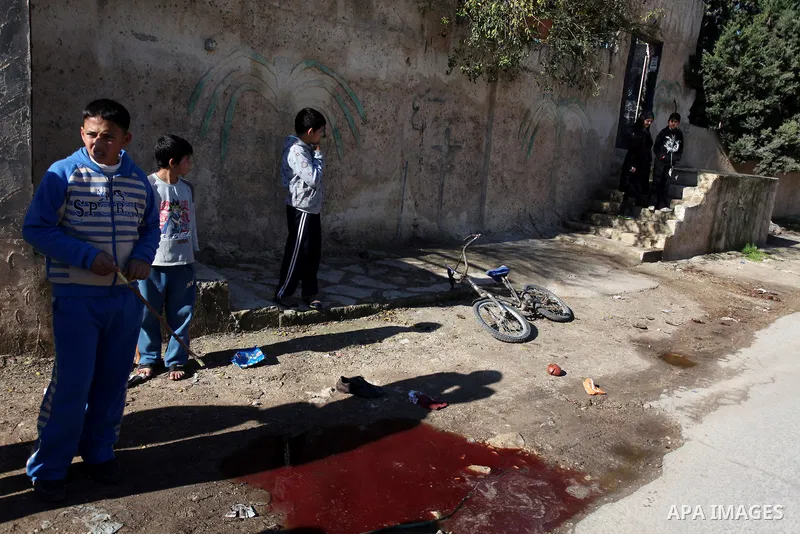 Palestinian children look at blood stains on the ground following a shooting attack in the northern West Bank town of Beit Rima, near Ramallah, on December 17, 2012. Photo by Issam Rimawi