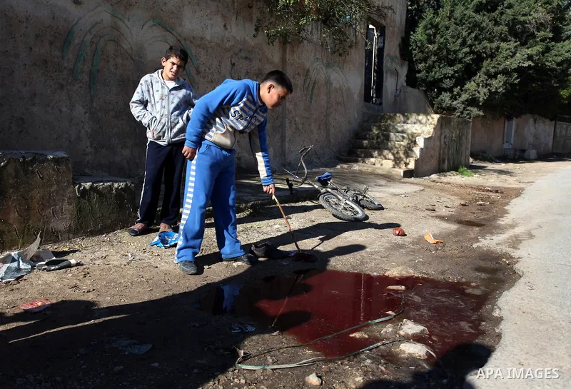 Palestinian children look at blood stains on the ground following a shooting attack in the northern West Bank town of Beit Rima, near Ramallah, on December 17, 2012. Photo by Issam Rimawi