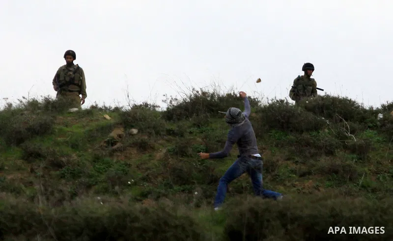 A masked Palestinian throws stones during clashes with Jewish settlers, not pictured, outside the West Bank village of Madama and the Jewish settlement of Yitzhar, near Nablus, Dec. 17, 2012. Photo by Nedal Eshtayah