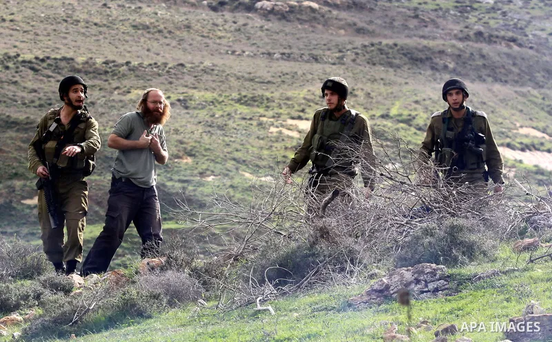 An Israeli soldier speaks with a Jewish settler during clashes with Palestinians, not seen, outside the West Bank village of Madama and the Jewish settlement of Yitzhar, near Nablus, Dec. 17, 2012. Photo by Nedal Eshtaya...