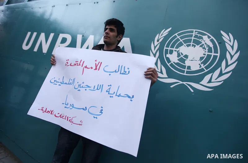 A Palestinian man holds placards during a protest in solidarity with Palestinian in al-Yarmouk refugee camp in Syria in In front of the United Nations headquarters in Gaza City on 18 December 2012. Pro-rebel sources repo...