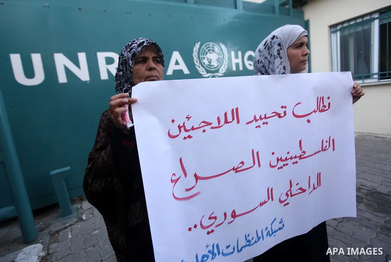 Palestinians hold placards during a protest in solidarity with Palestinian in al-Yarmouk refugee camp in Syria in In front of the United Nations headquarters in Gaza City on 18 December 2012. Pro-rebel sources reported t...