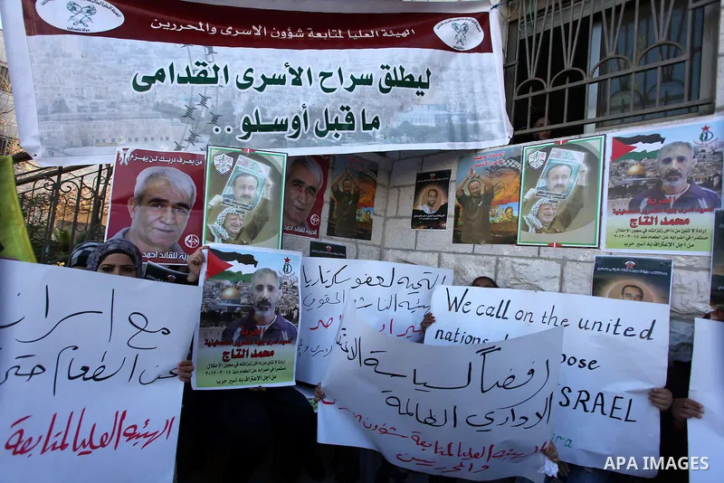 Palestinians hold pictures of prisoners held in Israeli jails during a sit-in outside the Red Crescent offices near the West Bank city of Ramallah on December 17, 2012. in solidarity with hunger-striking detainees held b...