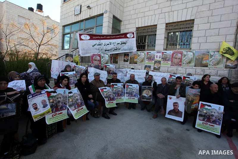 Palestinians hold pictures of prisoners held in Israeli jails during a sit-in outside the Red Crescent offices near the West Bank city of Ramallah on December 17, 2012. in solidarity with hunger-striking detainees held b...