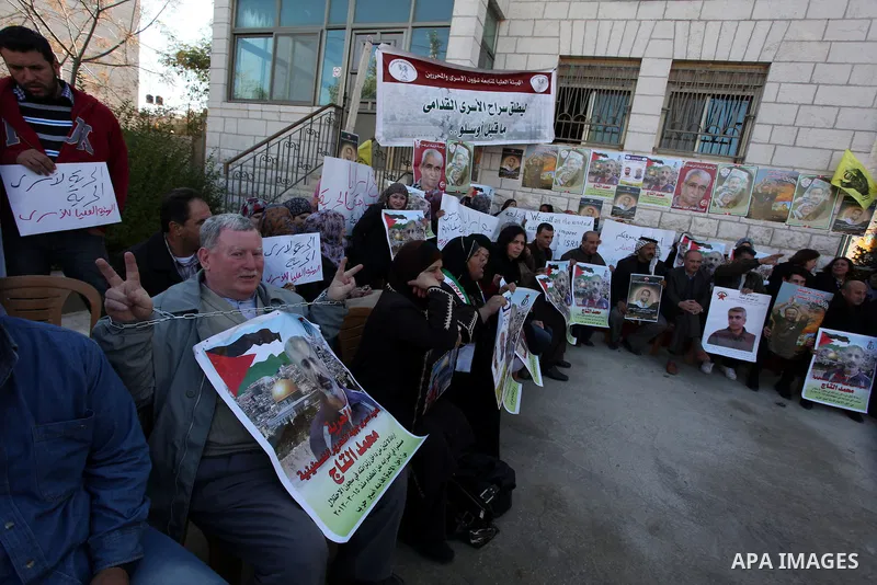 Palestinians hold pictures of prisoners held in Israeli jails during a sit-in outside the Red Crescent offices near the West Bank city of Ramallah on December 17, 2012. in solidarity with hunger-striking detainees held b...