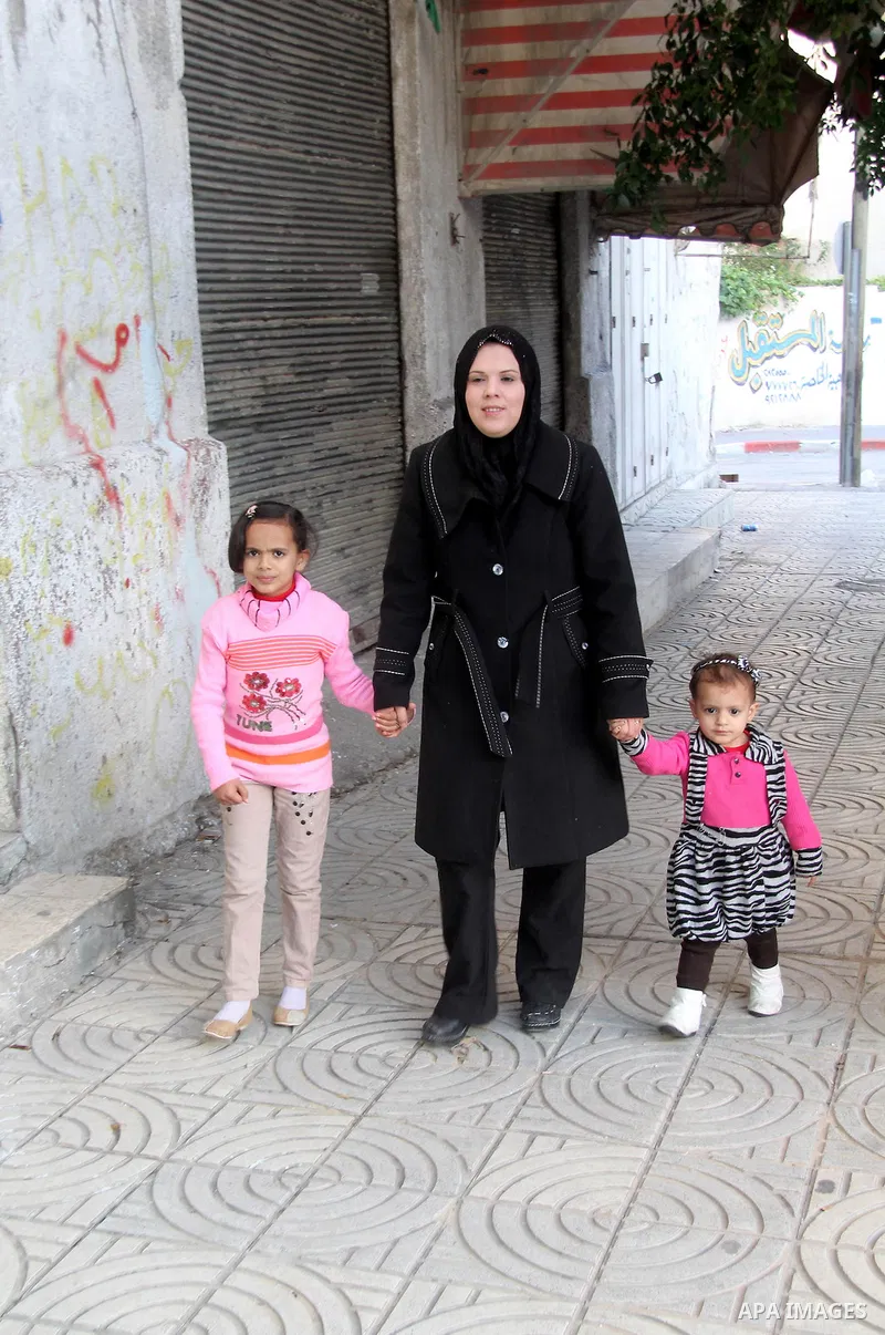 A Palestinian woman, Samar Bulbul walks with her family at a street in Gaza city on Dec. 18,2012. Bulbul lost hearing after an Israeli airstrike targeted two Palestinian militants' car in Gaza city in December 2011. Phot...