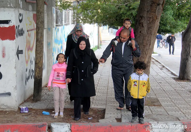 A Palestinian woman, Samar Bulbul walks with her family at a street in Gaza city on Dec. 18,2012. Bulbul lost hearing after an Israeli airstrike targeted two Palestinian militants' car in Gaza city in December 2011. Phot...