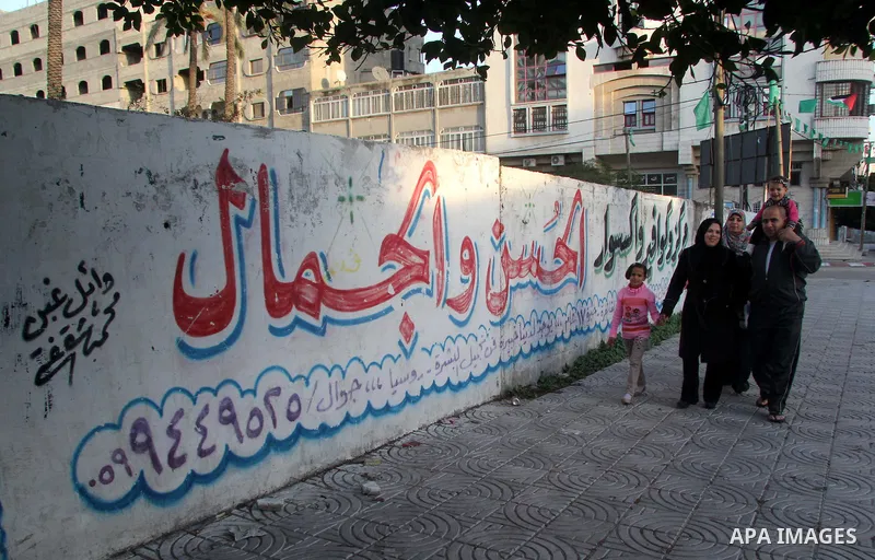 A Palestinian woman, Samar Bulbul walks with her family at a street in Gaza city on Dec. 18,2012. Bulbul lost hearing after an Israeli airstrike targeted two Palestinian militants' car in Gaza city in December 2011. Phot...