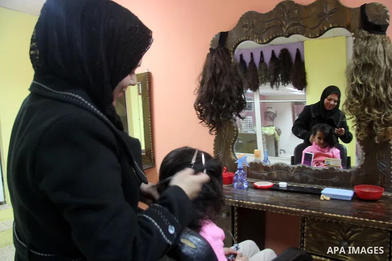 A Palestinian woman, Samar Bulbul prepares her daughter at her home in Gaza city on Dec. 18,2012. Bulbul lost hearing after an Israeli airstrike targeted two Palestinian militants' car in Gaza city in December 2011. Phot...