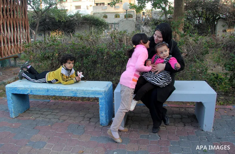 A Palestinian woman, Samar Bulbul plays with her kids at a park in Gaza city on Dec. 18,2012. Bulbul lost hearing after an Israeli airstrike targeted two Palestinian militants' car in Gaza city in December 2011. Photo by...