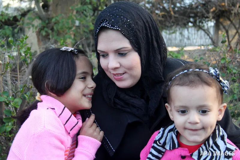 A Palestinian woman, Samar Bulbul plays with her kids at a park in Gaza city on Dec. 18,2012. Bulbul lost hearing after an Israeli airstrike targeted two Palestinian militants' car in Gaza city in December 2011. Photo by...