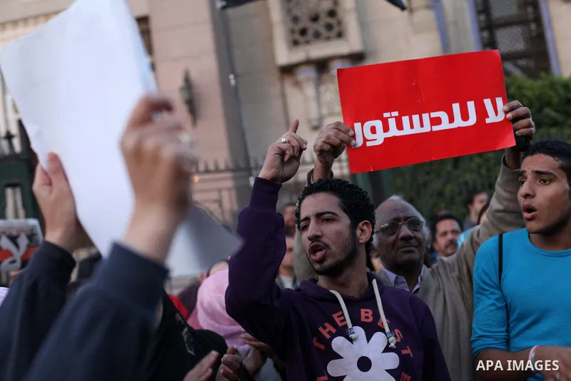 Egyptian protesters shout slogans against the President Mohamed Morsi and hold a banner reading in Arabic 'no to the constitution' during a demonstration against the draft constitution, in Cairo, Egypt, 18 December 2012....