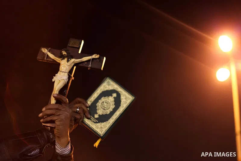 A man holds a copy of the Koran and a cross as she shouts slogans during a demonstration against Egypt's President Mohamed Mursi in front of the presidential palace in Cairo December 18, 2012. Opponents of Mursi staged p...