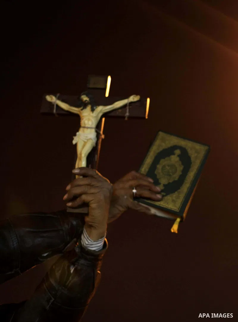 A man holds a copy of the Koran and a cross as she shouts slogans during a demonstration against Egypt's President Mohamed Mursi in front of the presidential palace in Cairo December 18, 2012. Opponents of Mursi staged p...