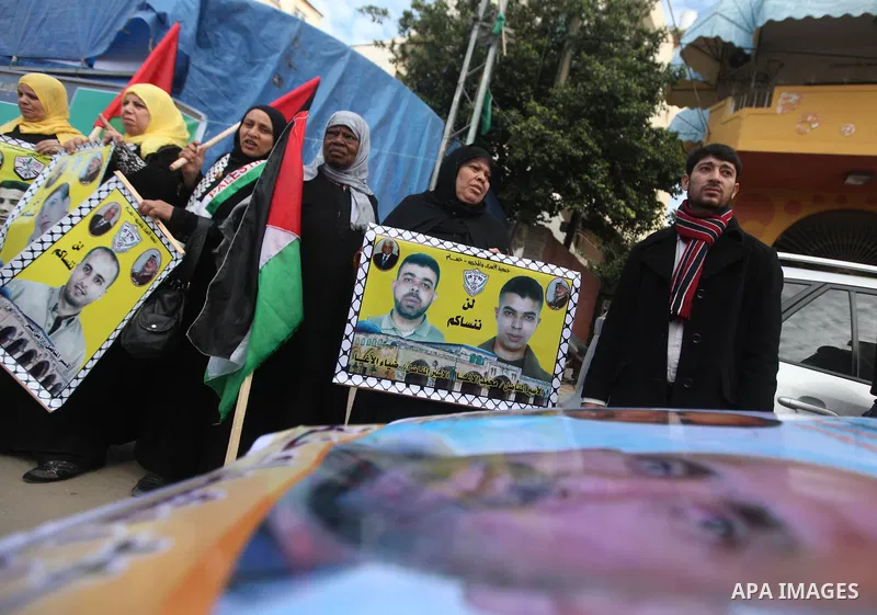 Palestinians hold pictures of prisoners held in the Israeli jails during a rally in Gaza city on December 19, 2012. in solidarity with hunger-striking detainees held by Israel to demand their release from detention witho...