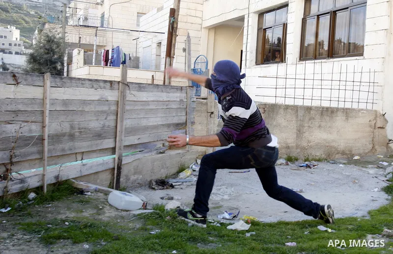 A masked Palestinian youth throws stones at Israeli soldiers during clashes in the Arab Jerusalem neighbourhood of Issawiya after a demonstration in solidarity with Palestinian prisoner Samer Issawi, held in an Israeli j...