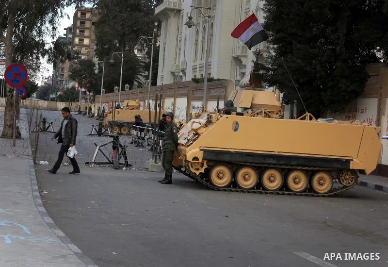 Egyptian army soldiers and tanks stand behind barbed wire as hundreds of opposition protesters arrive at the Presidential Palace in Cairo on December 19, 2012 during a demonstration against President Mohammed Morsi and t...