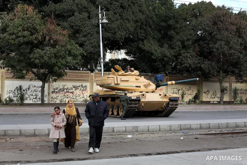 Egyptians walk pass the wire barricade as Egyptian army soldiers and tanks guard the presidental palace in Cairo December 19, 2012. Opponents of Egyptian President Mohamed Mursi staged protests in Cairo on Tuesday agains...