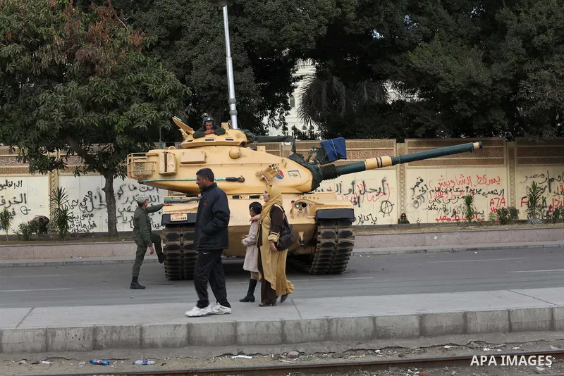 Egyptians walk pass the wire barricade as Egyptian army soldiers and tanks guard the presidental palace in Cairo December 19, 2012. Opponents of Egyptian President Mohamed Mursi staged protests in Cairo on Tuesday agains...