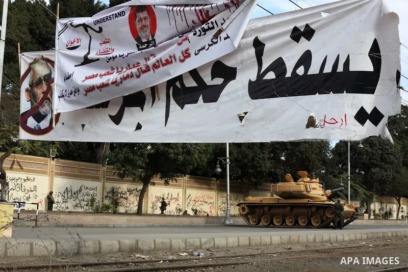 Egyptian army soldiers and tanks stand behind barbed wire as hundreds of opposition protesters arrive at the Presidential Palace in Cairo on December 19, 2012 during a demonstration against President Mohammed Morsi and t...