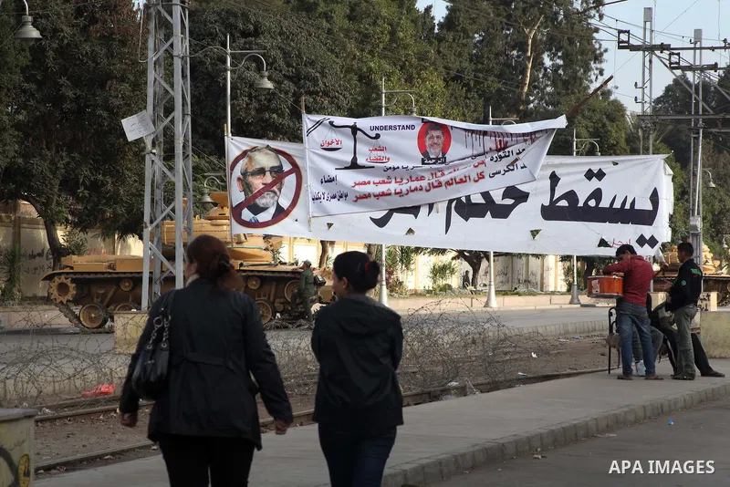 Egyptians walk pass the wire barricade as Egyptian army soldiers and tanks guard the presidental palace in Cairo December 19, 2012. Opponents of Egyptian President Mohamed Mursi staged protests in Cairo on Tuesday agains...