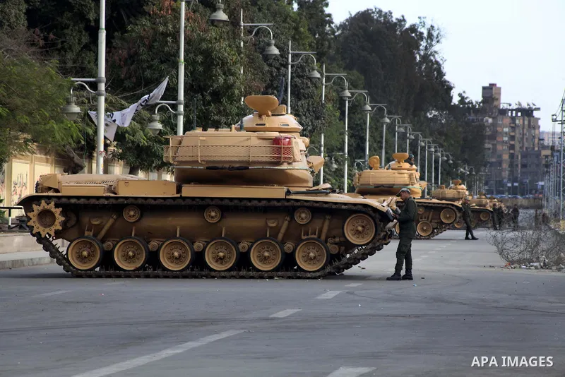Egyptian army soldiers and tanks stand behind barbed wire as hundreds of opposition protesters arrive at the Presidential Palace in Cairo on December 19, 2012 during a demonstration against President Mohammed Morsi and t...