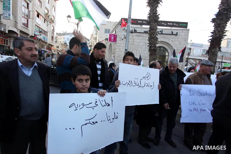 Palestinians hold placards during a protest in solidarity with Palestinian in al-Yarmouk refugee camp in Syria in the West Bank city of Ramallah on 19 December 2012. Pro-rebel sources reported that at least 25 Palestinia...