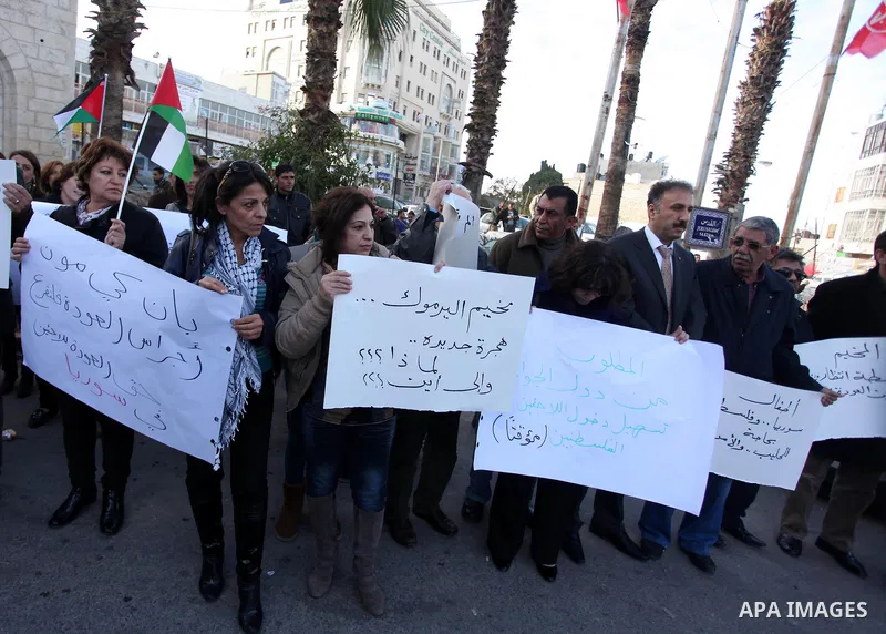 Palestinians hold placards during a protest in solidarity with Palestinian in al-Yarmouk refugee camp in Syria in the West Bank city of Ramallah on 19 December 2012. Pro-rebel sources reported that at least 25 Palestinia...