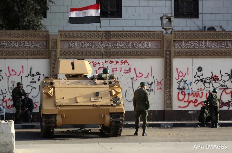 Egyptian army soldiers and tanks stand behind barbed wire as hundreds of opposition protesters arrive at the Presidential Palace in Cairo on December 19, 2012 during a demonstration against President Mohammed Morsi and t...