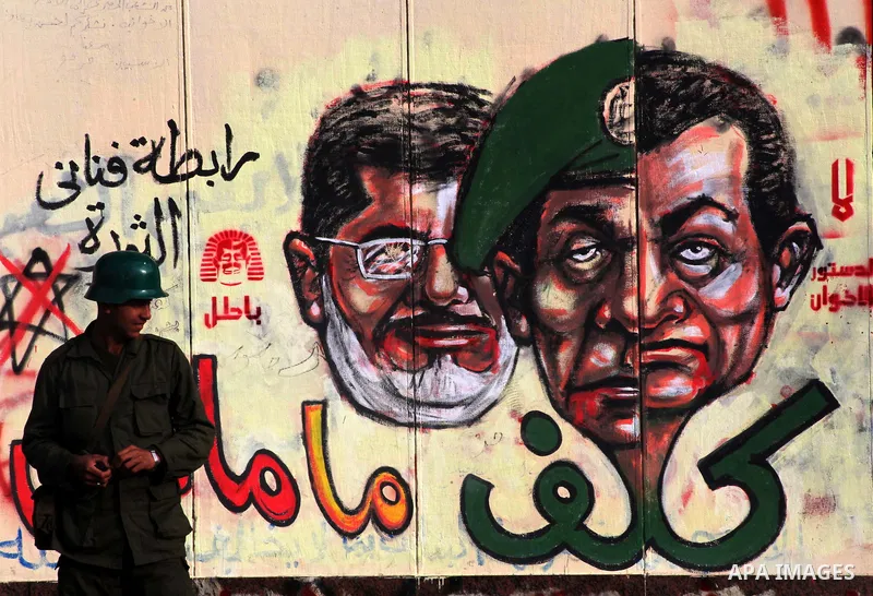 A republican guards soldier stands guard at the presidential palace and anti-Morsi graffiti is seen on the palace's wall behind him in Cairo, Dec. 18, 2012. Egypt's opposition staged rallies across the country on Tuesday...