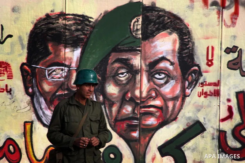 A republican guards soldier stands guard at the presidential palace and anti-Morsi graffiti is seen on the palace's wall behind him in Cairo, Dec. 18, 2012. Egypt's opposition staged rallies across the country on Tuesday...