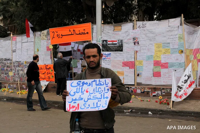 Egyptians opposition supporter stand at the presidential palace and anti-Morsi graffiti is seen on the palace's wall behind him in Cairo, Dec. 18, 2012. Egypt's opposition staged rallies across the country on Tuesday to...