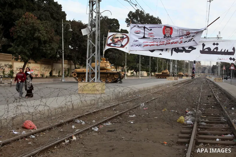 Egyptian army soldiers and tanks stand behind barbed wire as hundreds of opposition protesters arrive at the Presidential Palace in Cairo on December 19, 2012 during a demonstration against President Mohammed Morsi and t...
