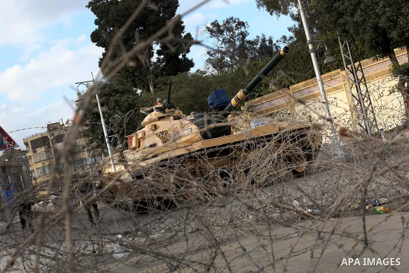 Egyptian army soldiers and tanks stand behind barbed wire as hundreds of opposition protesters arrive at the Presidential Palace in Cairo on December 19, 2012 during a demonstration against President Mohammed Morsi and t...