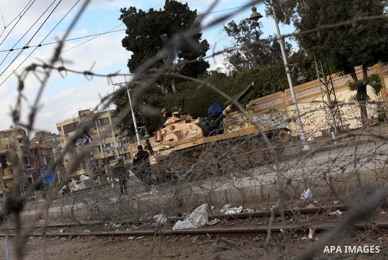 Egyptian army soldiers and tanks stand behind barbed wire as hundreds of opposition protesters arrive at the Presidential Palace in Cairo on December 19, 2012 during a demonstration against President Mohammed Morsi and t...