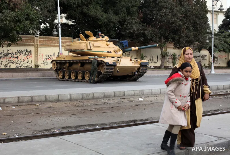 Egyptians walk pass the wire barricade as Egyptian army soldiers and tanks guard the presidental palace in Cairo December 19, 2012. Opponents of Egyptian President Mohamed Mursi staged protests in Cairo on Tuesday agains...