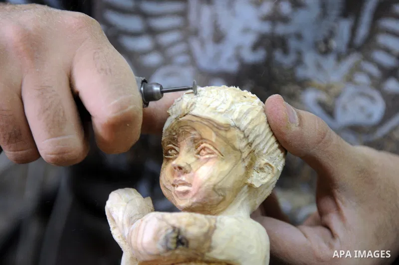 A Palestinian carpenter carves a wooden sculpture of baby Jesus at a workshop in the West Bank town of Bethlehem, on December 20, 2012. The traditional birthplace of Jesus Christ prepares to celebrate Christmas later thi...