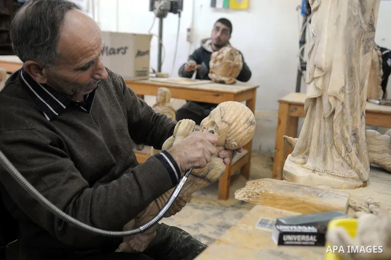 A Palestinian carpenter carves a wooden sculpture of baby Jesus at a workshop in the West Bank town of Bethlehem, on December 20, 2012. The traditional birthplace of Jesus Christ prepares to celebrate Christmas later thi...
