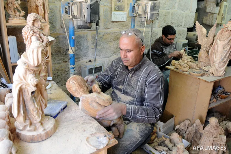 A Palestinian carpenter carves a wooden sculpture of baby Jesus at a workshop in the West Bank town of Bethlehem, on December 20, 2012. The traditional birthplace of Jesus Christ prepares to celebrate Christmas later thi...
